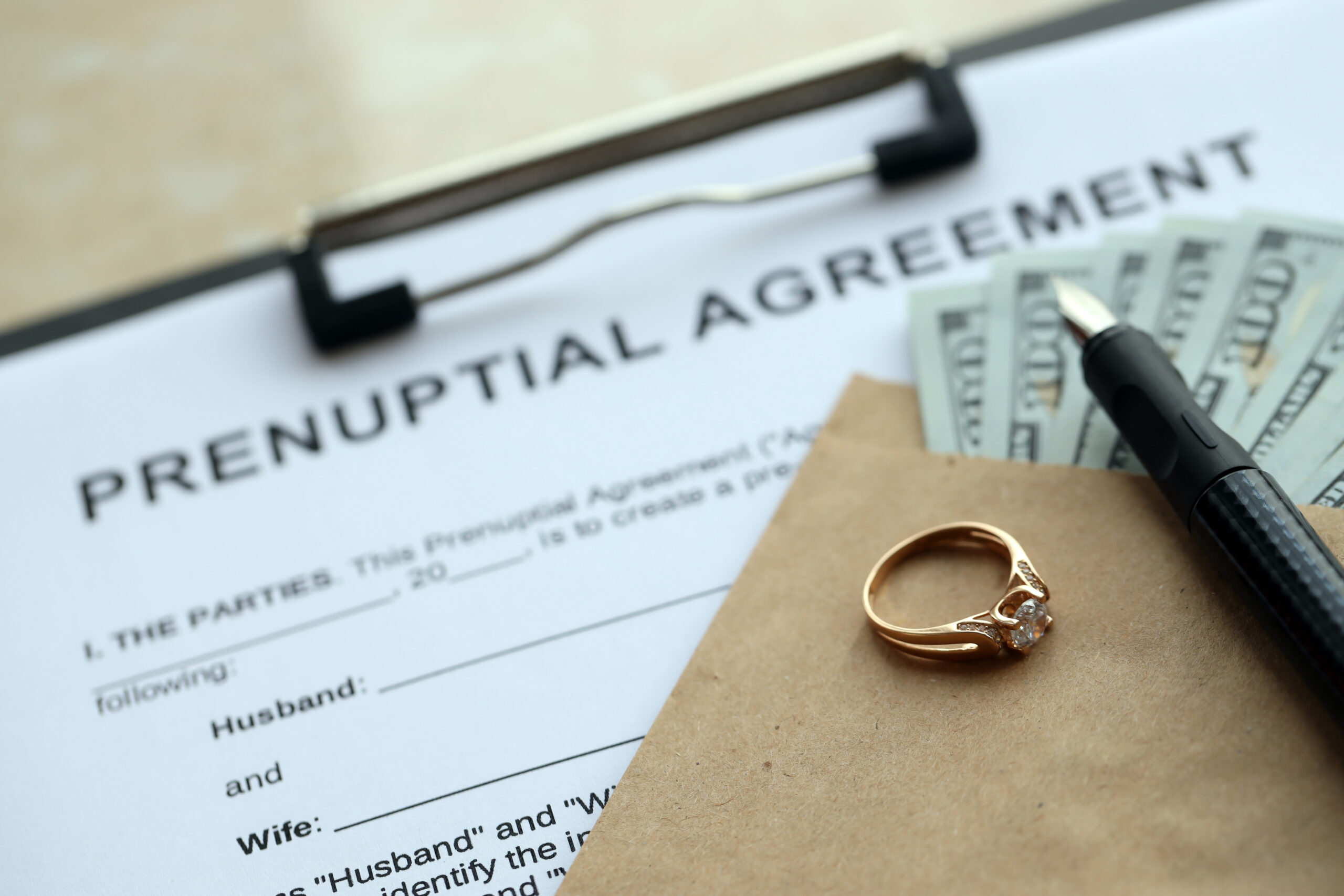 Prenuptial agreement and wedding ring on table. Premarital paperwork process in USA