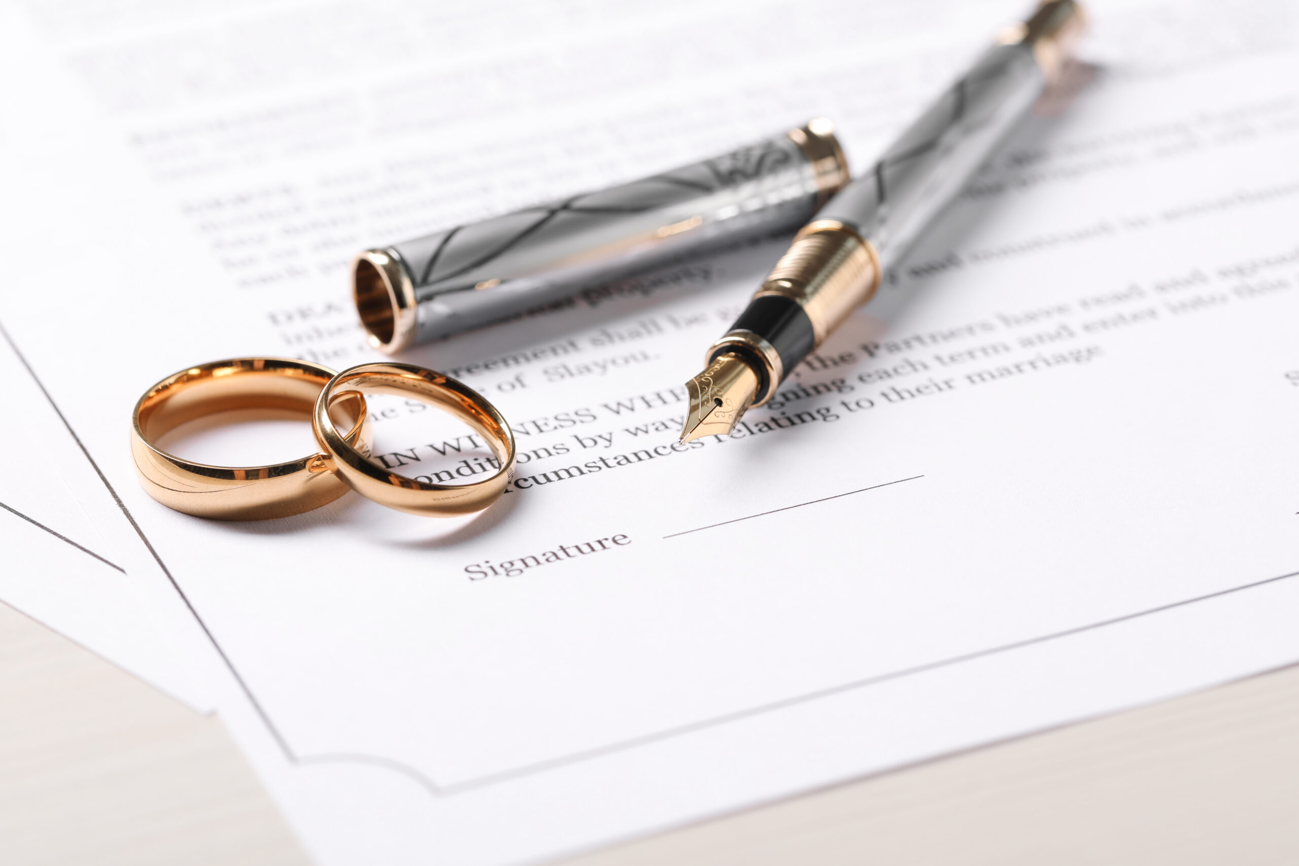 Marriage contracts, gold rings and pen on light wooden table, cl